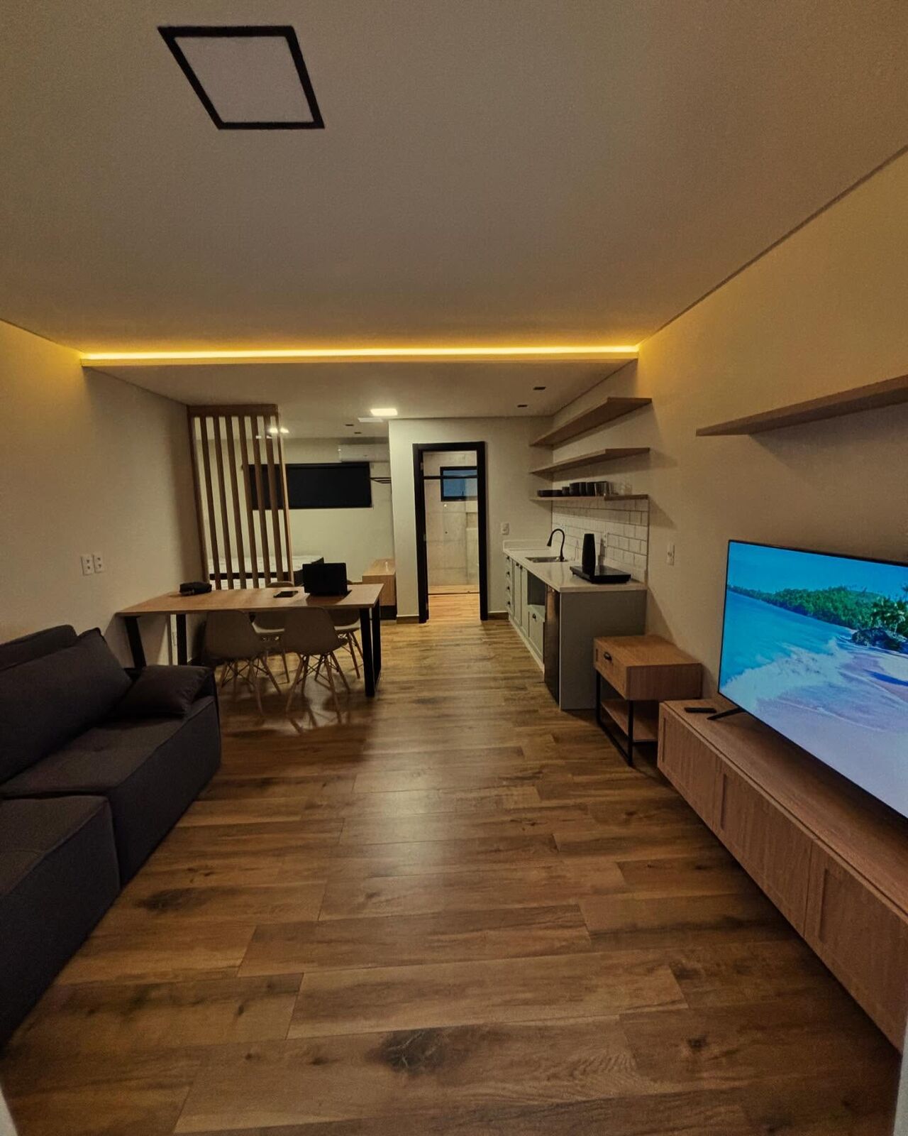 Sala de um dos lofts, com madeira clara e iluminação aconchegante